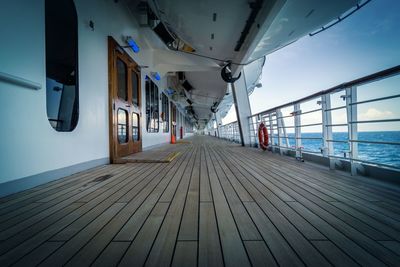 Empty walkway by sea against sky