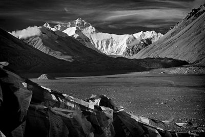 Praying flags by snow covered mountains against sky