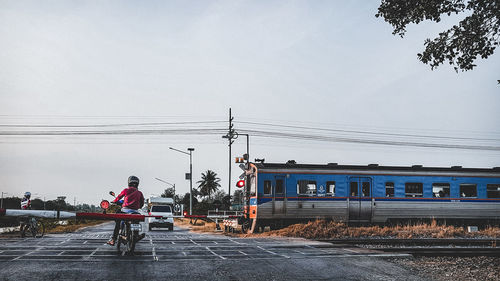 People on railroad tracks against sky