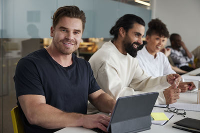 Man sitting at business meeting with digital tablet and looking at camera