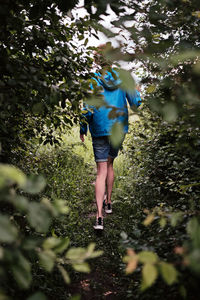 Rear view of woman walking on street amidst trees