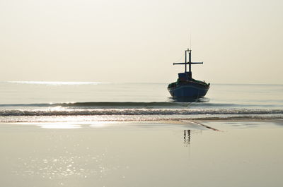 Sailboat on sea shore against sky