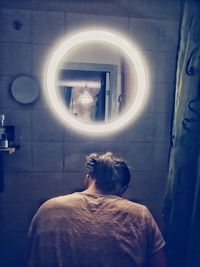Rear view of man standing by window