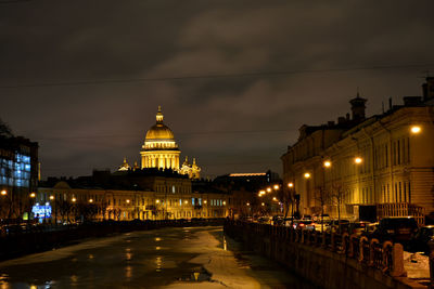 Frozen canal amidst buildings in city against sky at night