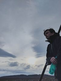 Low angle view of young man looking away against sky