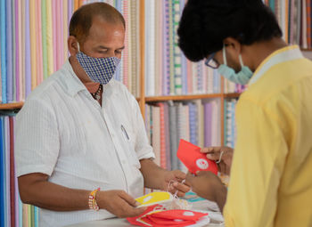 Midsection of young man buying flu mask at store