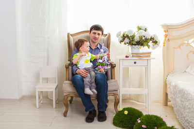 Full length of father and son sitting on chair