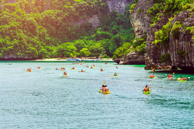 Group of people sailing in sea against mountains