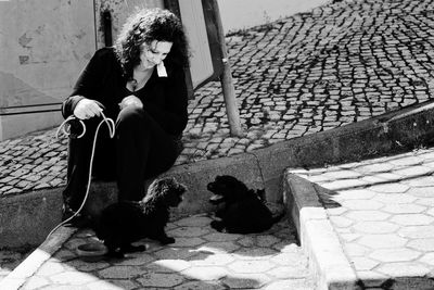 Full length of smiling woman looking at puppies