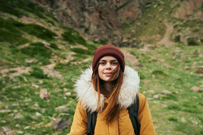 Portrait of young woman standing against trees