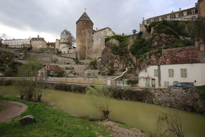 Buildings by river against sky