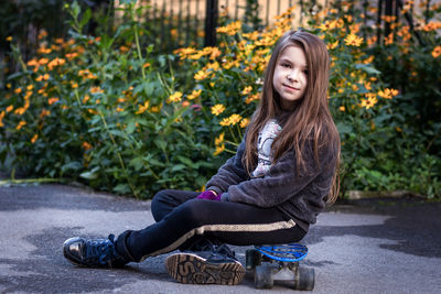 Portrait of young woman sitting on footpath