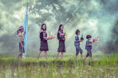 Full length of children standing on field against sky