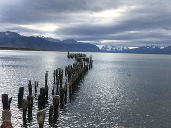 Wooden posts in lake against sky