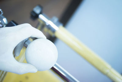 Cropped hand of person holding white ball at home