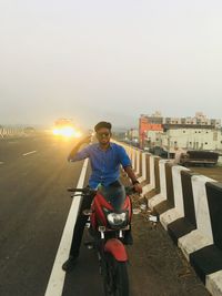 Man riding motorcycle on road against sky in city