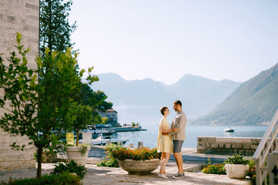 Couple standing on mountain against sky