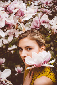 Portrait of young woman amidst pink flowers
