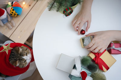 Cropped hands of woman with christmas decoration on table