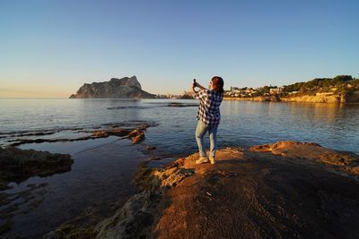 Rear view of man standing on rock at beach