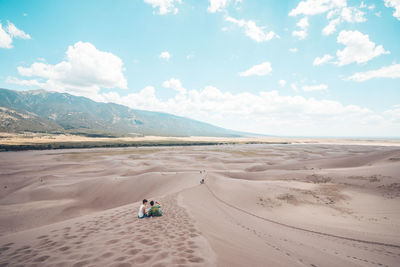 Scenic view of people on desert against sky