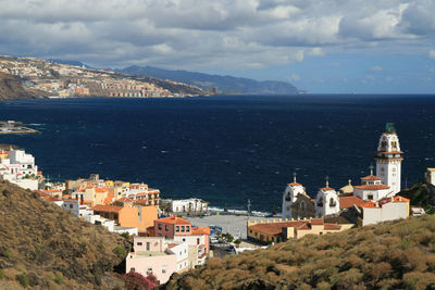 High angle shot of townscape by sea against sky