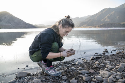 Woman putting mud on hands and face while enjoying outdoors in nature.