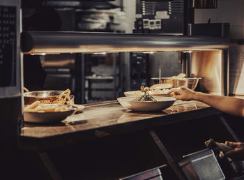 A food waiter picks up a plate from a food serving counter. 