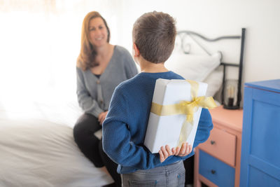 Llittle boy hiding a gift for his mother on mothers day