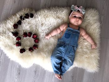 Directly above view of baby girl lying by red roses on white rug at home