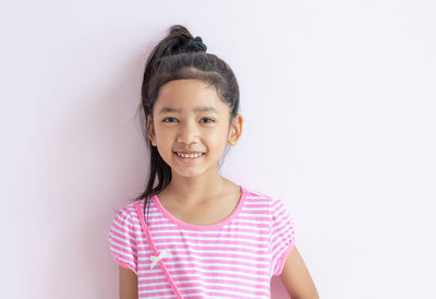 Portrait of a smiling girl standing against white background