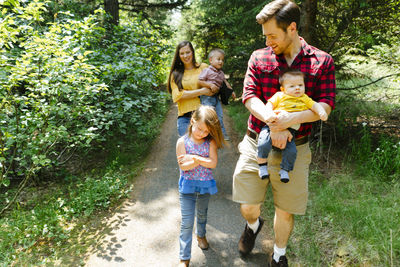 Straight on view of a family of five hiking through the forest