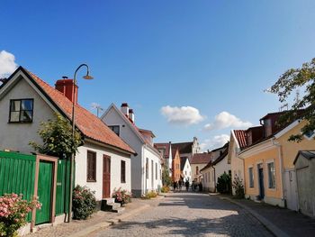 Street amidst houses against blue sky