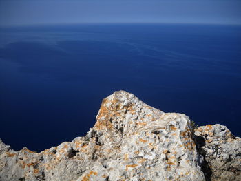 Rock formations by sea against blue sky