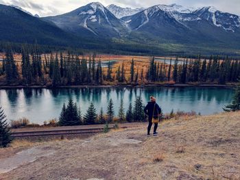 Rear view of woman standing on mountain against lake