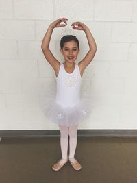 Portrait of ballerina dancing against white wall