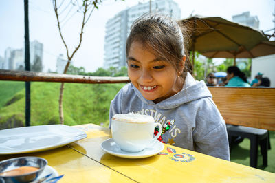 Portrait of young woman using mobile phone while sitting on table