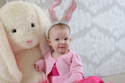 Portrait of baby girl sitting with stuffed toy at home