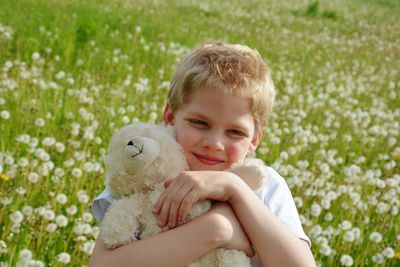 Close-up portrait of boy holding teddy bear on field