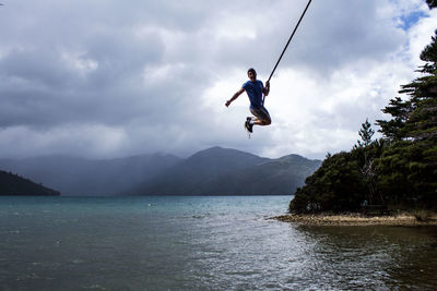 Man jumping in sea against sky