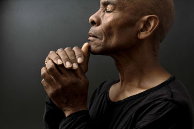 Black man praying to god on gray background with people stock image stock photo