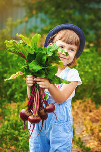 Portrait of smiling young woman standing against plants