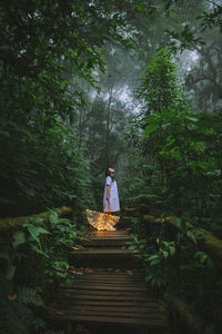 Woman standing amidst trees in forest