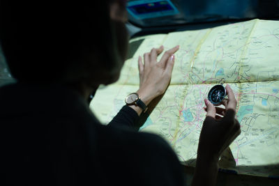 Close-up of woman holding navigational compass over map