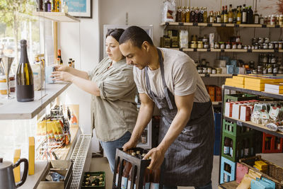 Male and female owners helping each other while working in wine shop