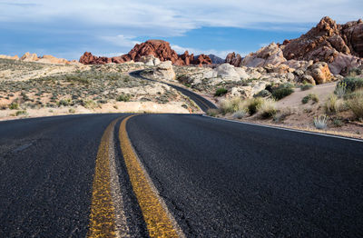 Road by desert against sky