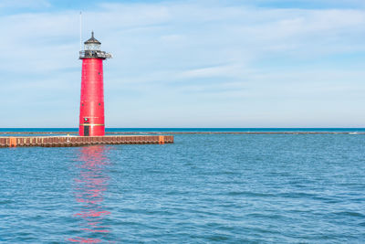 Lighthouse by sea against sky