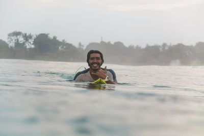 Portrait of happy man lying on surfboard on the sea