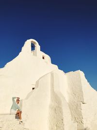 Woman sitting outside chapel on sunny day