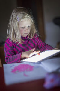 Girl using digital tablet on desk at home